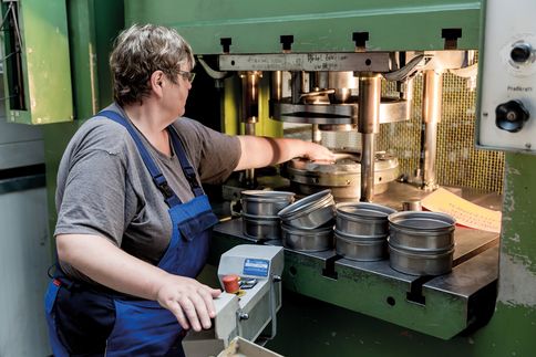 Eine ältere Frau steuert eine Produktionsanlage