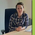 Eine junge Frau sitzt sehr gut gelaunt an einem Computerarbeitsplatz