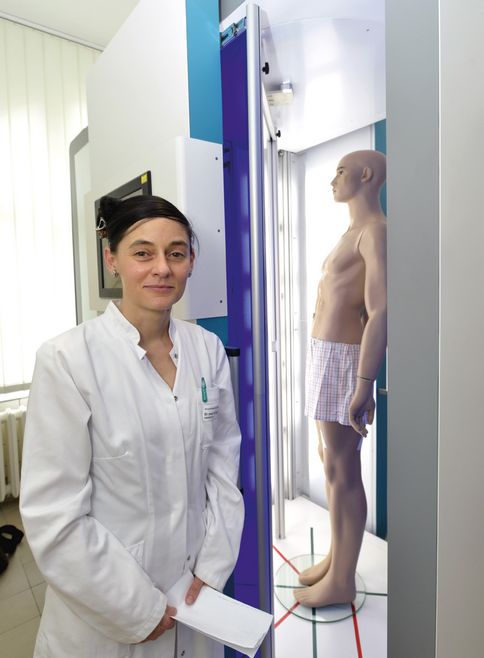 Eine Frau im weißen Kittel steht vor einem Röntgenapparat