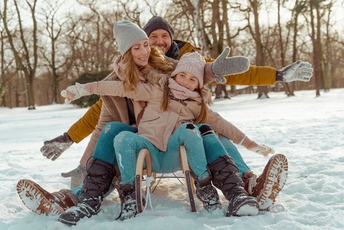 Eine gut gelaunte Familie sitzt auf einem Schlitten