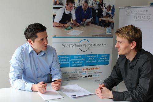 Zwei Männer sitzen an einem Tisch und unterhalten sich.