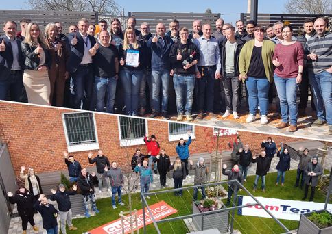 Zwei Fotos: auf dem oberen steht eine große Gruppe draußen, sie zeigen den Daumen nach oben, eine Person hält eine Urkunde. Auf dem zweiten Foto sind Personen von oben fotografiert, sie gucken hoch und winken in die Kamera