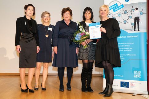 5 Personen stehen auf einer Bühne und bekommen das Landessiegel