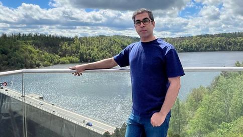 Ein junger Mann steht vor einem Stausee